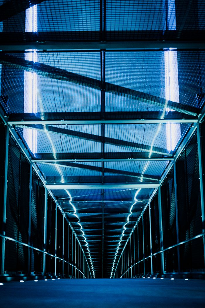 A low-angle view of a futuristic steel tunnel with blue lighting, creating a modern and vibrant atmosphere.