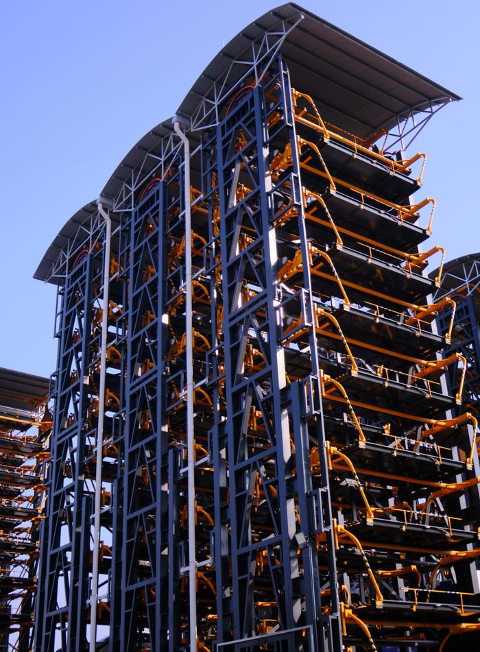 View of a modern automated parking system with metal frameworks against a blue sky.